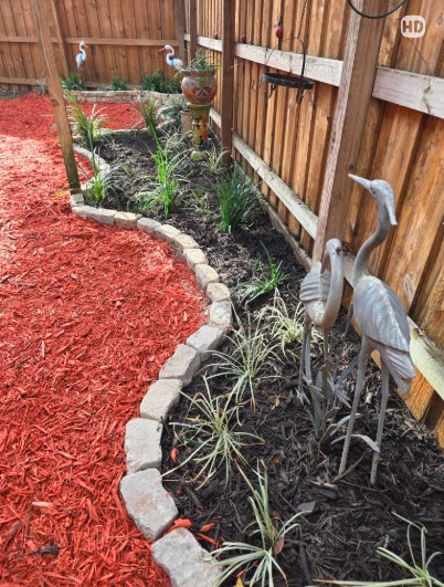 Boardman Lawncare red mulch bed with stone edging and plantings