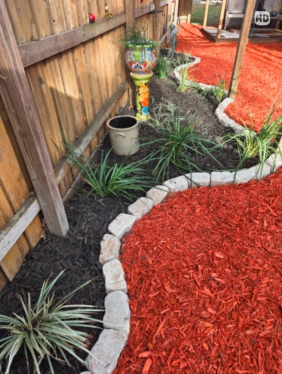 Boardman Lawncare red mulch bed with stone edging and plantings